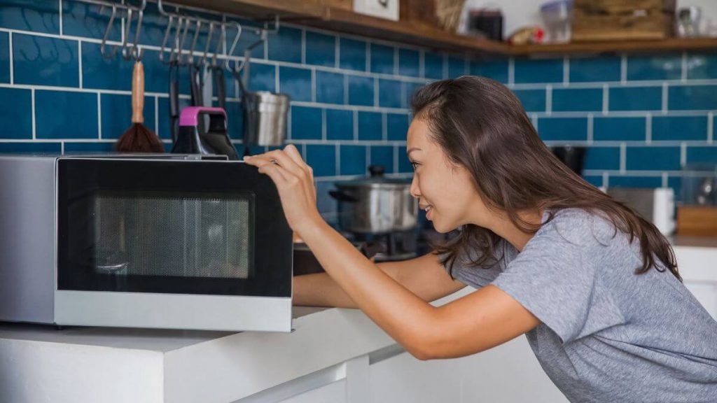 women reheating crumbl cookies in microwave